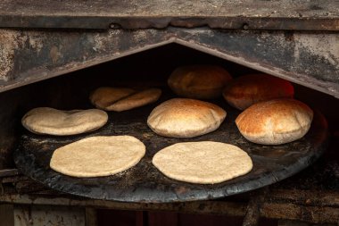 Kudüs 'te geleneksel bir pazarda sıcak taş fırında pide pişiriliyor. Ekmekler şişiyor, kahverengileşiyor, otantik Orta Doğu sokak yemekleri sergiliyor..