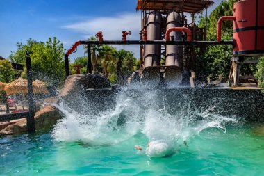  Ziyaretçiler Caneva Aquapark 'taki bir su yolculuğundan havuza dalarken dramatik bir sıçrama yapıyorlar. İtalya 'nın en popüler su parklarından birinde canlı ve enerjik bir yaz sahnesi..
