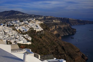 Yunanistan 'ın Santorini kentindeki Ege Denizi' ne bakan havuzları ve şemsiyeleri olan teraslı beyaz binalar. Lüks mimari, volkanik kayalıklar ve okyanus manzarası mükemmel bir yolculuk yeri yaratır..