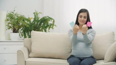 Genç hamile bir kadının mavi ve pembe çıkartmaları birleştirdiği 4K yavaş çekim videosu. Yaratıcılık kavramı.