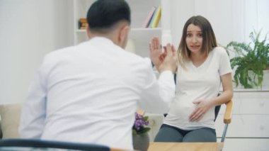 Hamile bir kadının doktorla konuştuğu 4K yavaş çekim videosu. Doktoru ziyaret etme kavramı.