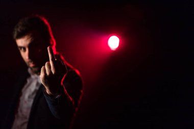 Pembe ve siyah arka planda orta parmağını gösteren bir adamın yakın plan fotoğrafı. İnsanın orta parmağını göstermesi kavramı.