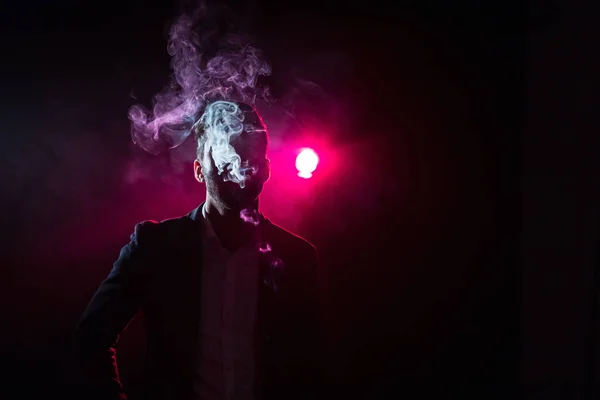 Photo of man in smoke on black and pink background. Concept of male model.