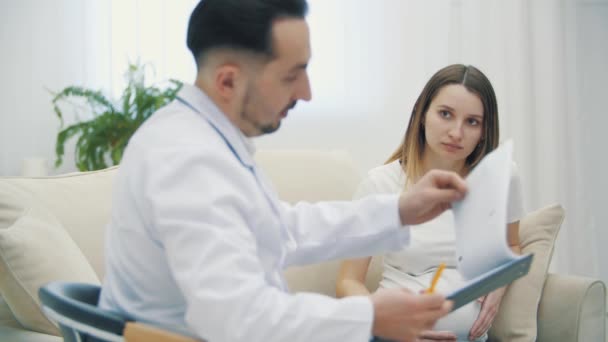 妊娠中の女性とカメラを見ている医者の4Kスローモーションビデオ 医者に行くという概念 — ストック動画