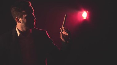 4K yavaş çekim videosunda takım elbiseli sigara içen adam ve arka planda pembe ışık. Sigara içen adam kavramı.