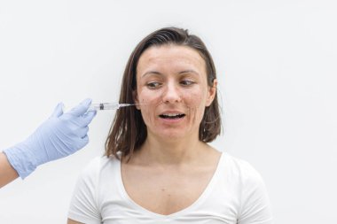 Kadının kameraya sakin ve üzgün bir bakışla, kuru bir ciltle ve cildine enjekte edilmiş tıbbi eldivenle bakışını yakından çek. Dermatoloji kavramı.