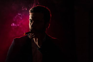 Pembe arka planda sigara içen adamın fotoğrafı. Sigara içme kavramı.