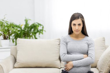 Photo of pregnant woman hugging her stomach on the couch in the living room . Concept of pregnant woman.