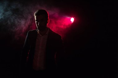 Ayakta duran adamın fotoğrafı ve arka planda pembe ışık. Takım elbiseli adam kavramı.