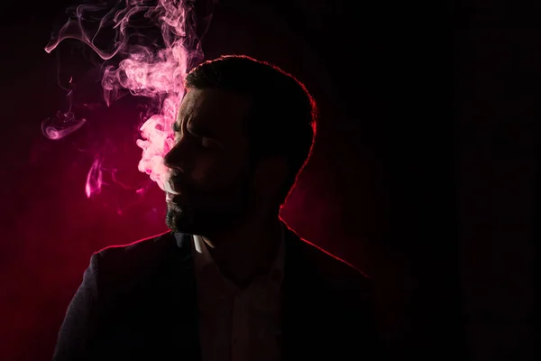 Photo of smoking man on pink background. Concept of smoking.