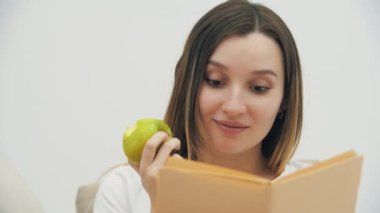 4k slowmotion video of pregnant woman looking at the camera and holding apple and book. Concept of pregnant woman.