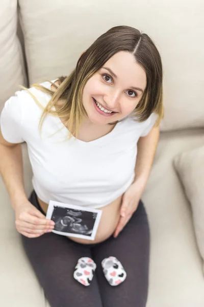 Photo of smiling pregnant woman with ultrasound result. Concept of pregnant woman.