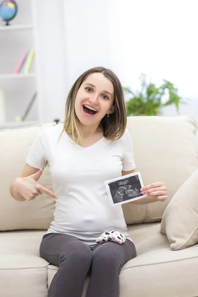 Photo of smiling pregnant woman with ultrasound result. Concept of pregnant woman.