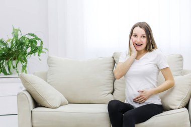 Photo of pregnant woman touching her cheek and stomach. Concept of prennant woman.