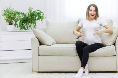 Photo of young woman excited about her pregnancy. Concept of pregnant woman emotions.