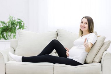 Young pregnant woman looking at the camera and showing thumb up. Concept of pregnant woman.