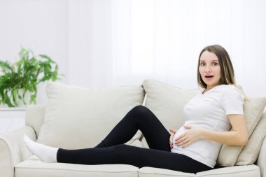 Pregnant woman looking at the camera and touching stomach. Concept of pregnant woman.