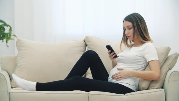 Spowolnienie Wideo Kobiety Ciąży Siedzi Białej Kanapie Telefonu Pojęcie Kobiety — Wideo stockowe