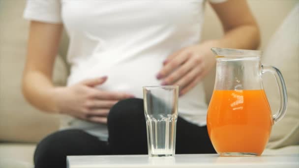 妊娠中の女性の4Kのスローモーションビデオがオレンジジュースをグラスに注ぎ込む 妊娠中の女性のコンセプト — ストック動画