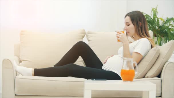 Slowmotion Video Pregnant Woman White Sofa Drinking Orange Juice Concept — Vídeo de Stock