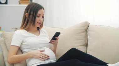 4k slowmotion video of pregnant woman texting with smile. Concept of pregnant woman.