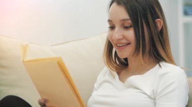 Hamile bir kadının kameraya bakıp kitap tutarken 4K yavaş çekim videosu. Hamile kadın kavramı.