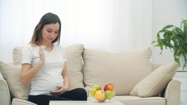 Spowolnienie Wideo Ciężarnej Kobiety Siedzącej Białej Kanapie Pojęcie Kobiety Ciąży — Wideo stockowe
