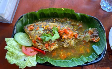 Hindistan cevizi sütü soslu kızarmış balık ve papaya yaprağı. Endonezya, Bali 'deki en popüler yemeklerden biri.