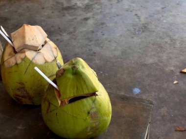 Hindistan cevizi ve hindistan cevizi masada. Tropik yaz içkisi, iki yeşil hindistan cevizi suyu ahşap koltukta müşterilere teslim etmeye hazır.
