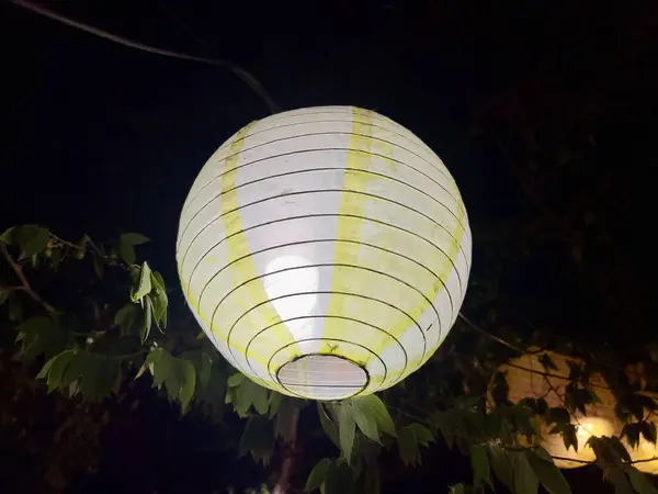 Gece arkaplanındaki bir restoranda yuvarlak şekilli lampion ışığı örtüsü.