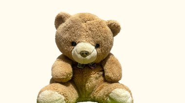 Kahverengi oyuncak ayı ön tarafa bakan peluş hayvan. Krema arka planında izole edilmiş.