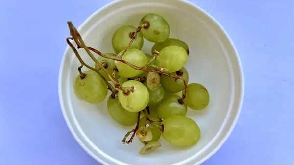 Beyaz arka planda plastik bir kasede taze yeşil üzümlerin yüksek çözünürlüklü yakın çekimi. Yemek blogları, sağlıklı yaşam tarzı kavramları, menüler veya organik ürün ambalajları için mükemmel.