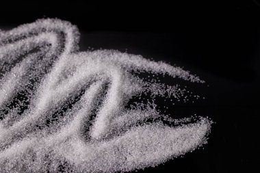 Beyaz şeker, siyah arkaplanda bir avuç şeker.