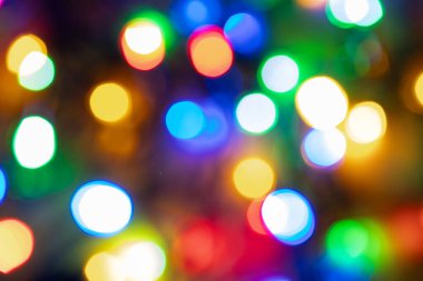 Noel arkaplanı bulanık. Soyut sırayla hareket eden koyu siyah arkaplanda çok renkli bulanık ışıklar. Bokeh ve röfleler bulanık. Yeni yıl. Bulanık arkaplan.