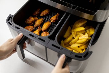 Patates kızartması (patates kızartması) ve tavuklu tavuk kanadı kızartma makinesinde pişirilmiş.