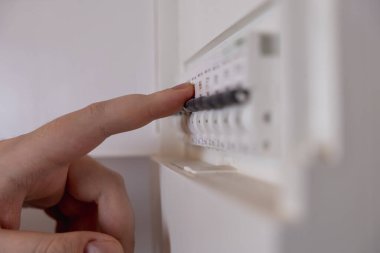 Elektrik sayacında elektrik düğmelerini değiştiren bir adamın yakın çekimi. Işık için ödeme