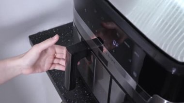 Kavrulmuş tavuk kanatları ve çekmeceyi çeken bir fritöz.