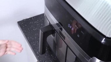 Kavrulmuş tavuk kanatları ve çekmeceyi çeken bir fritöz.