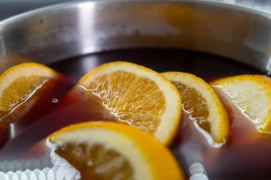 Close-up of orange slices floating in mulled wine mixture during preparation clipart