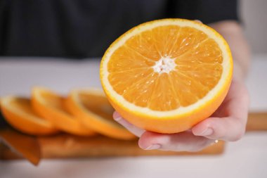 Arka planda sulu, canlı ve taze dilimlenmiş bir portakal sunar.