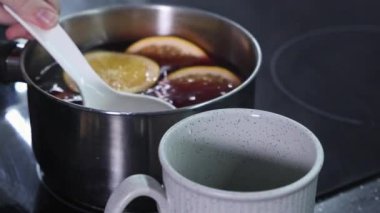 ... portakal dilimli kepçeyle seramik fincana yakınlaştırılmış şarap.