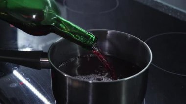 Kırmızı şarap bir tencereye döküldü ve şişe ocağın üzerine eğildi. Sıcak şarap hazırlıyorum.