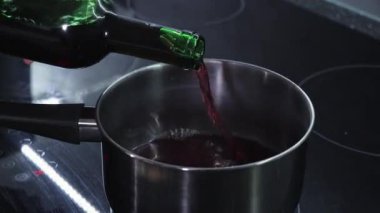 Ocaktaki bir tencereye kırmızı şarap dökerek yakınlaştım. Sıcak şarap hazırlıyorum.