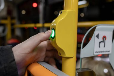 Otobüs durağındaki istek düğmesine basan adam, şehir içi ulaşımın, ulaşımın ve yolcu hareketlerinin altını çiziyor