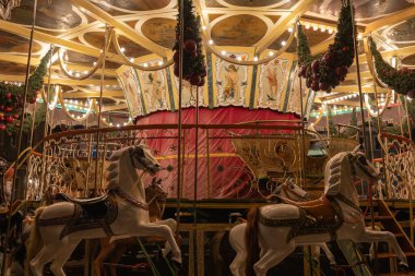 Atlı klasik atlıkarınca ve geceleri festival ışıkları, geleneksel eğlence gezisi, süslü detaylar, tatil süslemeleri, aydınlatılmış panayır manzarası, sıcak atmosfer.