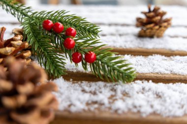 Kırmızı böğürtlen ve köknar dalı, karlı ahşap arka planda kozalaklı kozalaklar, kış tatili dekorasyonu, kır tarzı, doğadan esinlenilmiş festival düzenlemesi, rahat atmosfer.