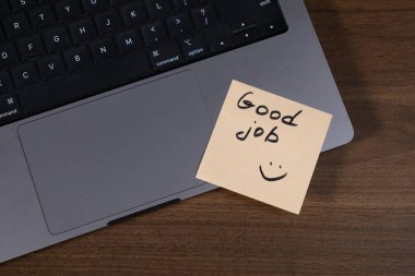 Motivasyon ve teşvik için klavyeye iyi iş mesajı bırakılmış yapışkan not