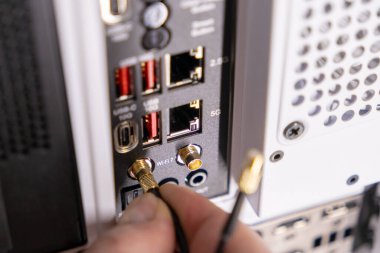 Wi-Fi antenini Pc io paneline bağlayan kullanıcı 5g ve usb portlarını modern beyaz masaüstü kutusunda, teknoloji ve bağlanabilirliği vurguluyor 