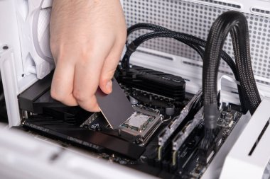 applying thermal paste to cpu using a spreading tool during pc assembly, close-up on motherboard and processor installation clipart