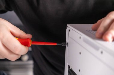 Bilgisayardaki vidaların sıkılması, eldeki tornavida, bilgisayar parçaları montajı, yan panel kurulumu 